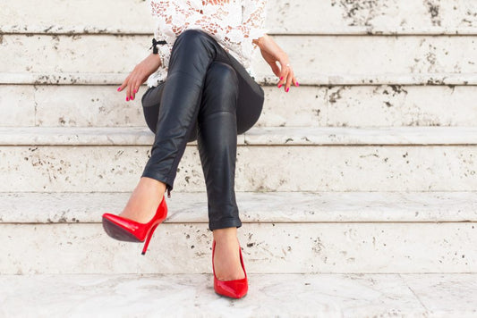 Woman wearing leather leggings and red heels sitting on steps