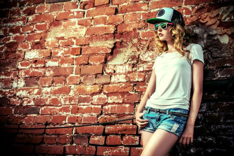 Woman in t-shirt styled with denim shorts, baseball hat, and sunglasses