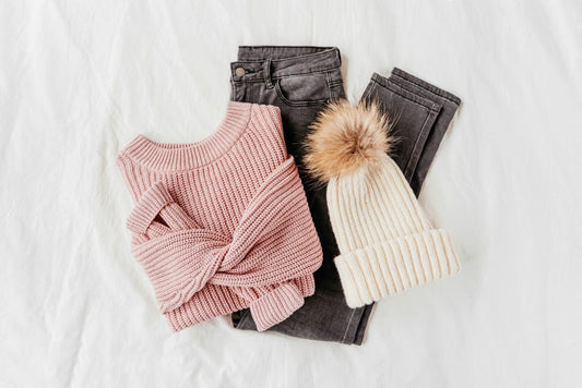 Winter outfit with gray jeans, pale pink sweater, and white beanie